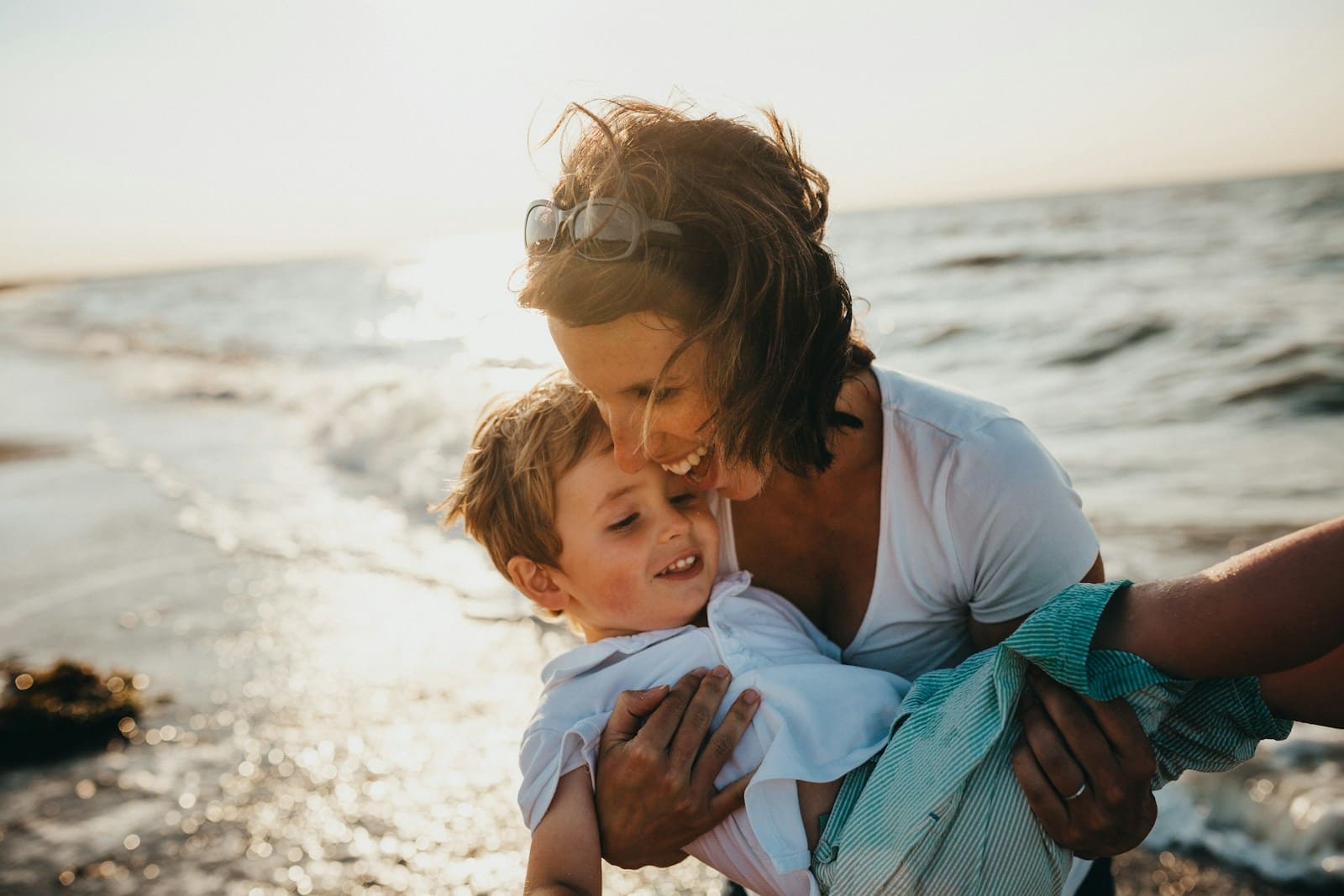 Madre e hijo riendo juntos en la playa