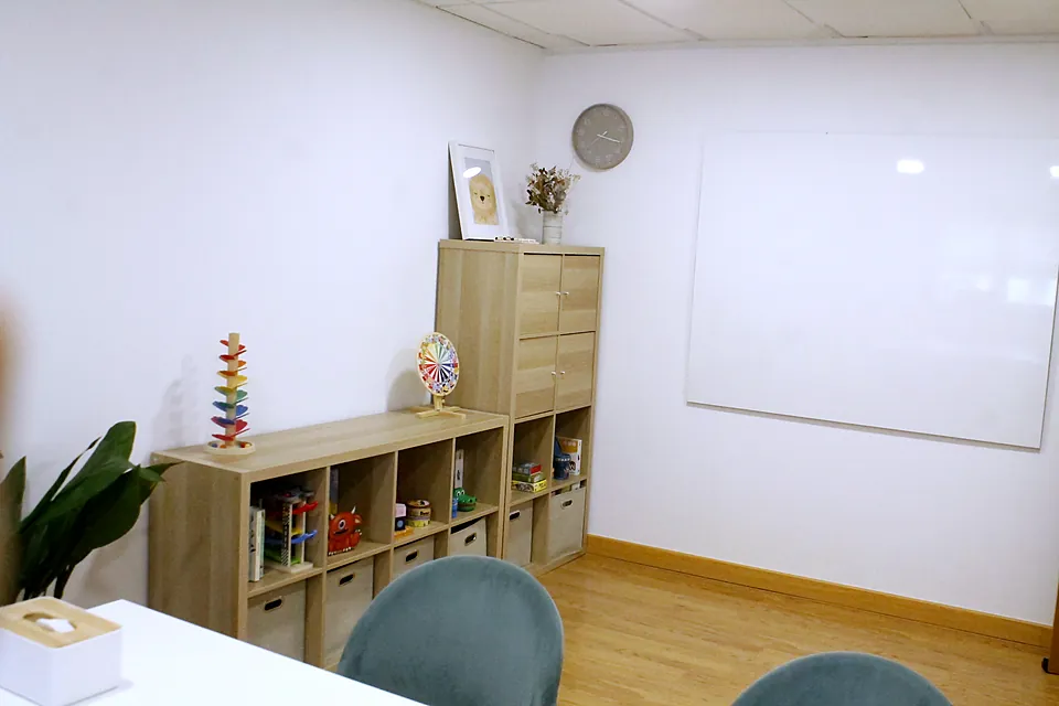 Sala de trabajo con estantería de juegos y pizarra blanca
