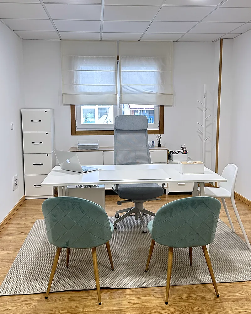 Consulta de psicología con mesa blanca y sillas verde salvia